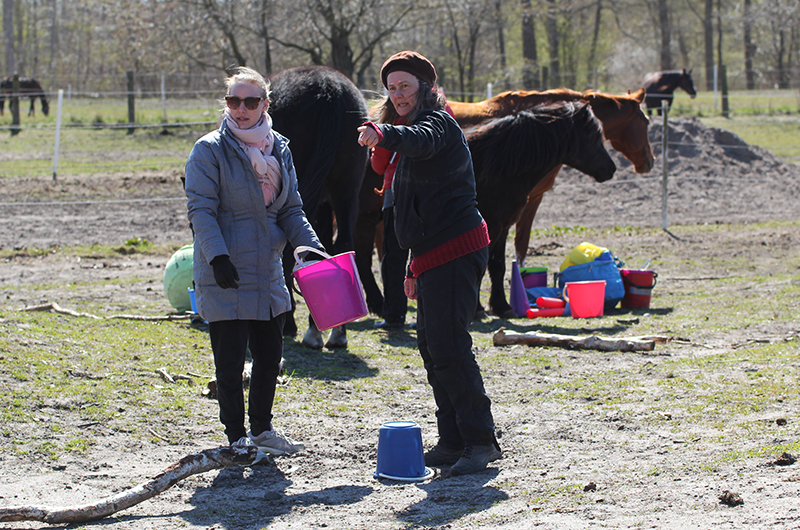 Two women horses in the background